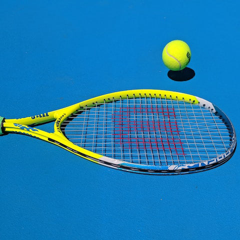tennis racket on a blue court with a tennis ball