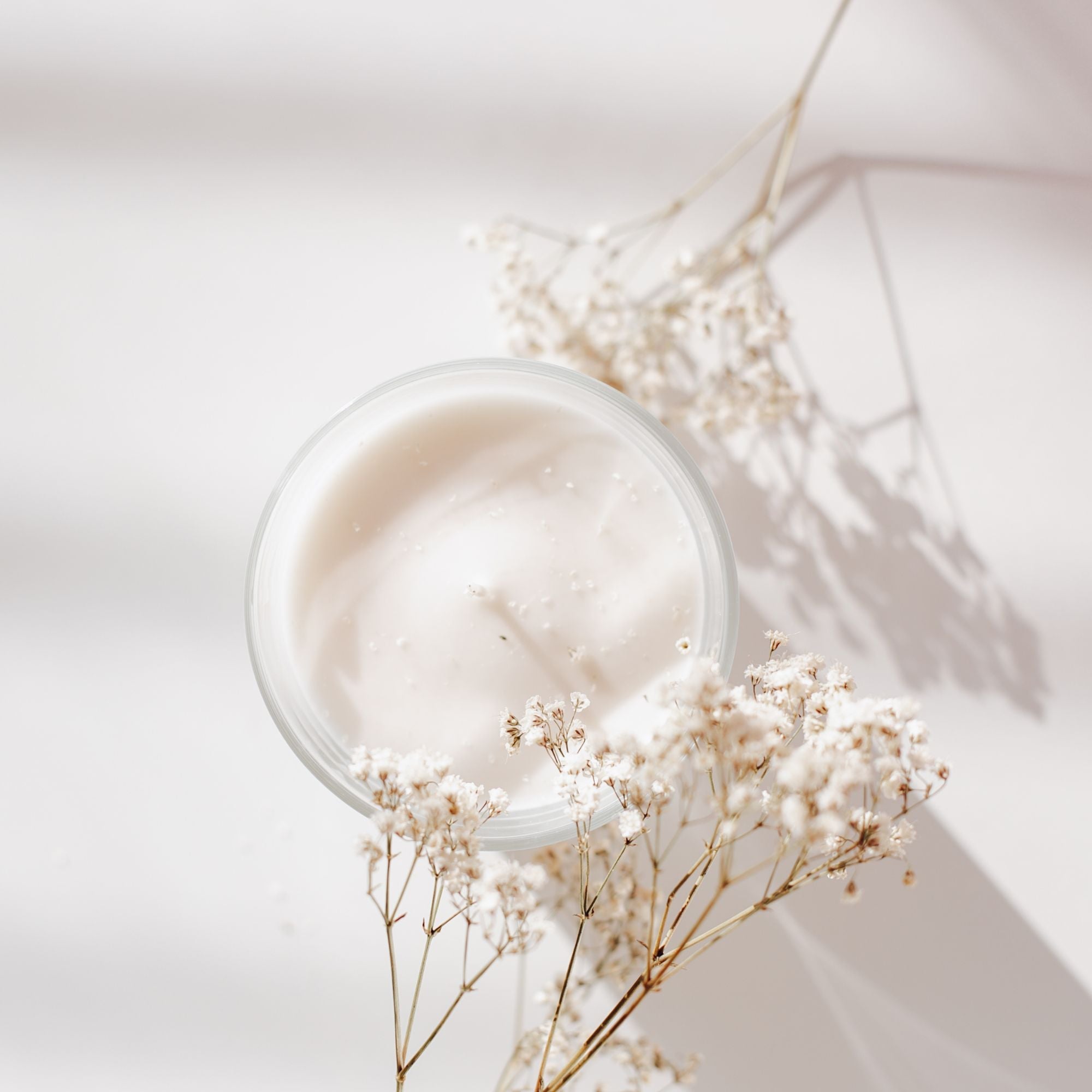 jar with cream with dried flower next to it