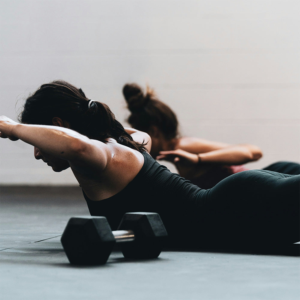 2 women doing mat pilates with weight on floor