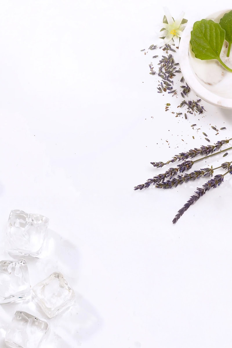 white background with lavender twigs, marble bowl filled with cream, and ice cubes